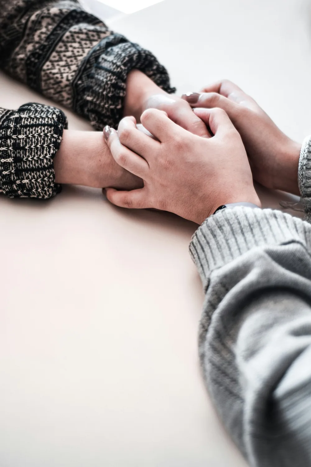 Two people sitting together, one hand resting over another