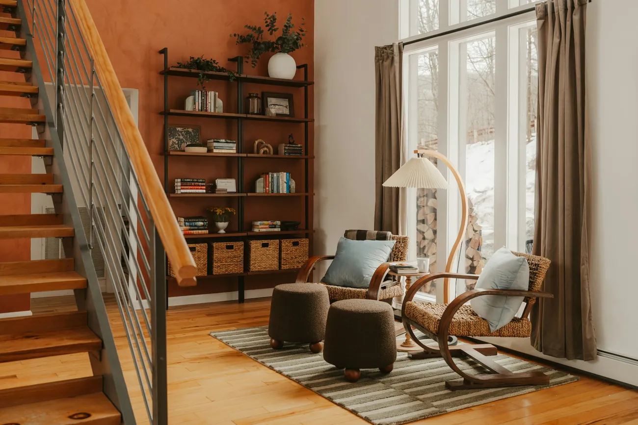 A warm room with two chairs, a bookshelf, and daylight from a large window